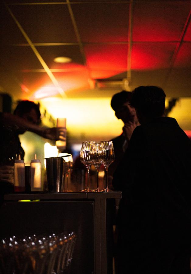 Invités au bar à cocktails dans une lumière rouge et ambrée