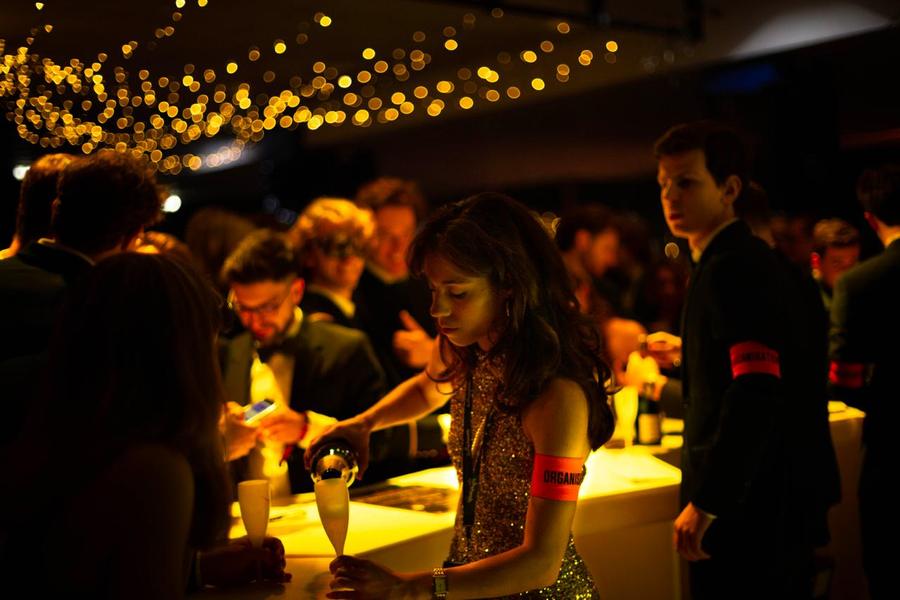 Invitée servant une coupe au bar à champagne, sous les guirlandes lumineuses