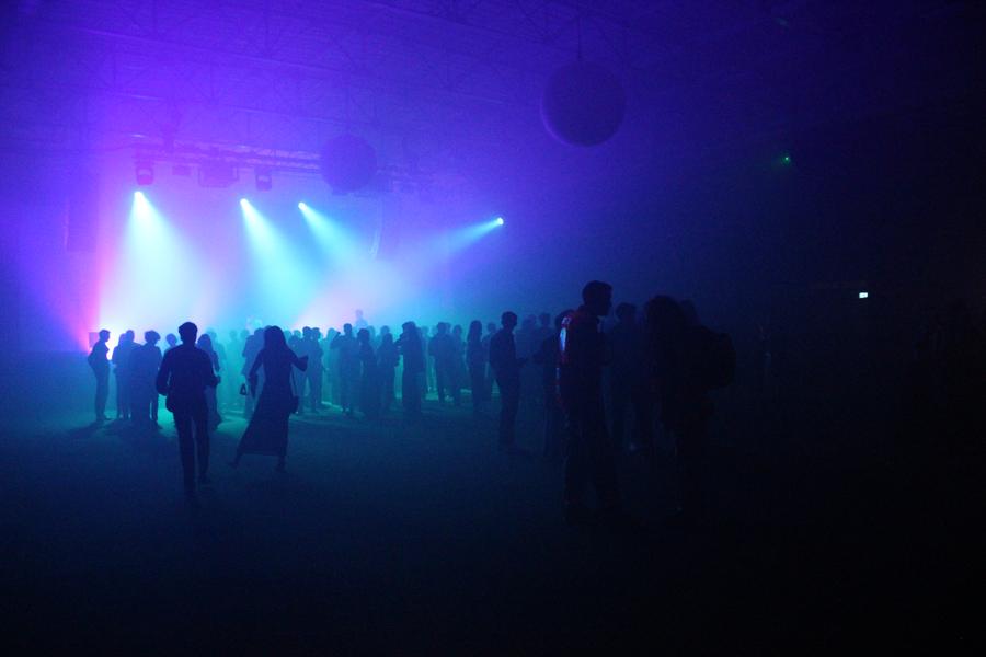Silhouettes des invités sur la piste de danse, sous des faisceaux bleus et violets